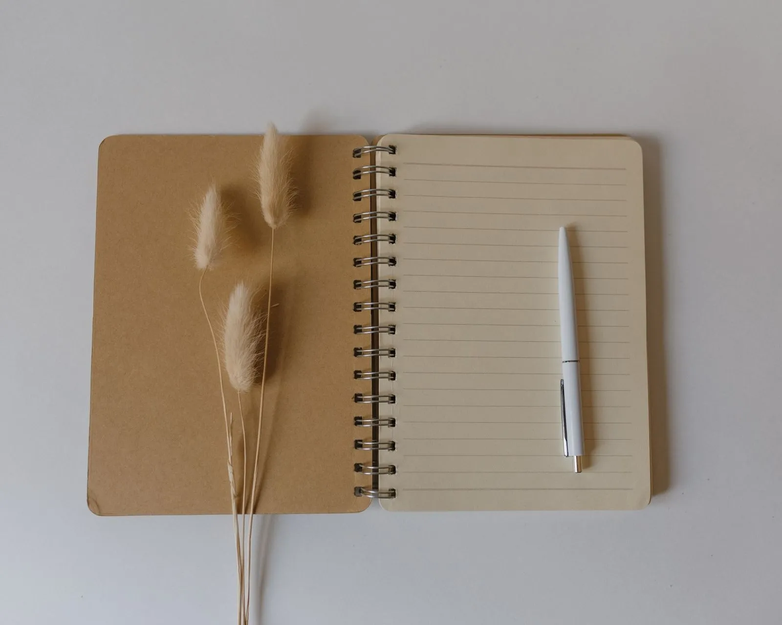 An open kraft notebook with a white pen